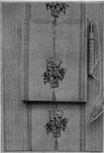 A pretty memorandum tablet suitable for a morning room or bedroom. Care should be taken to make the flap of wallpaper over the block lift easily. If backed with cardboard, it will not become crumpled by use