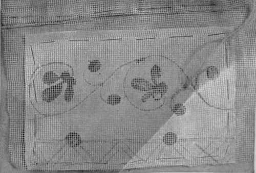 The design tacked in position under the material that is to be worked