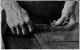 Fig. 87. Breaking off a narrow piece of glass with the pliers.
